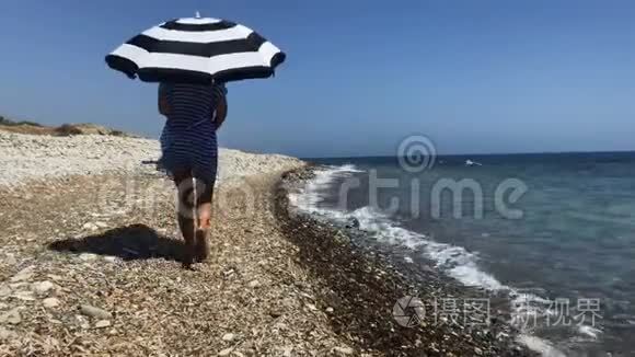 女人带着雨伞在海滨散步视频