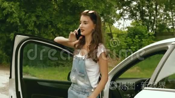 一位戴眼镜的时髦女士站在她的车旁边，用手机说话