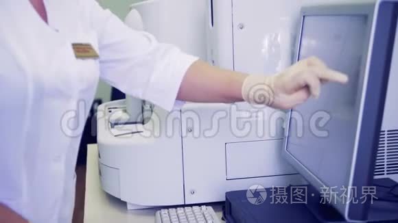 护士在监视器上打字，同时在机器上进行血液测试。 4K.