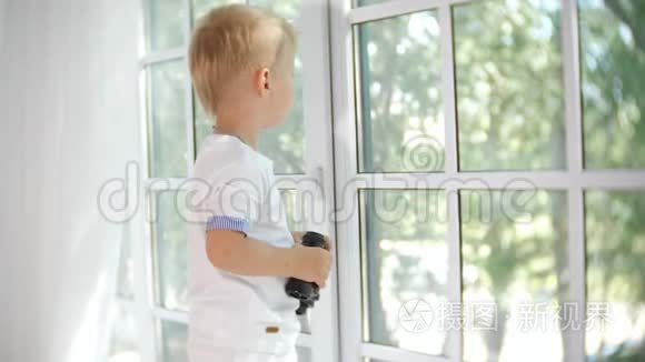 好奇的小男孩用望远镜看着窗外