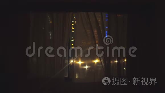 年轻人跑到窗户边，打开窗帘，欣赏夜晚从窗户上看到的风景。 4k，3840x2160