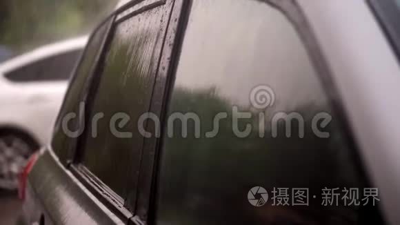 从外面看，有大雨，阵雨，水滴落在空黑车的彩色窗户上