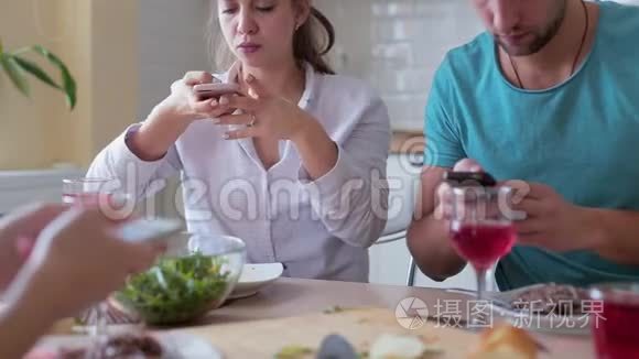 一群在家吃饭时看智能手机的朋友
