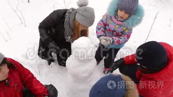 有孩子的大家庭在公园里堆雪人。