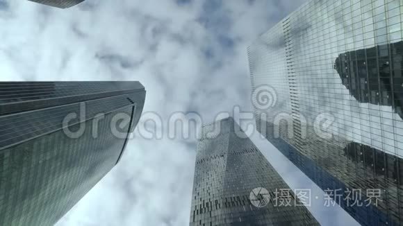 在多云的天空背景下看到现代摩天大楼的底部。