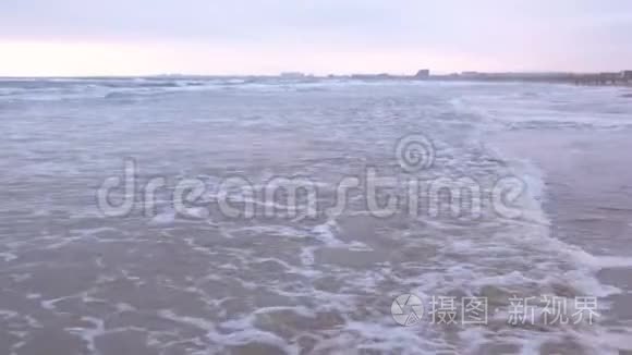 大海里波涛汹涌. 美丽的海景与沙滩和海岸小镇背景在日落。