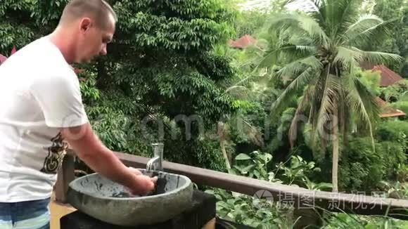 男人在外面用美丽的热带景色洗手洗脸。 新鲜度和生态理念.. 巴厘岛。
