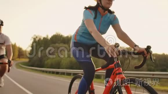 一对骑自行车的夫妇在日落时分骑着自行车走在公路上，在高处玩耍
