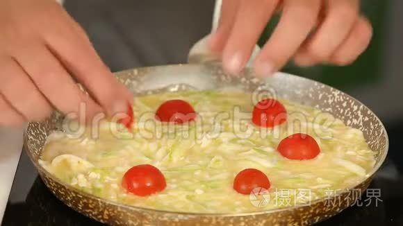 煎锅里放着樱桃番茄做鸡蛋蛋卷视频