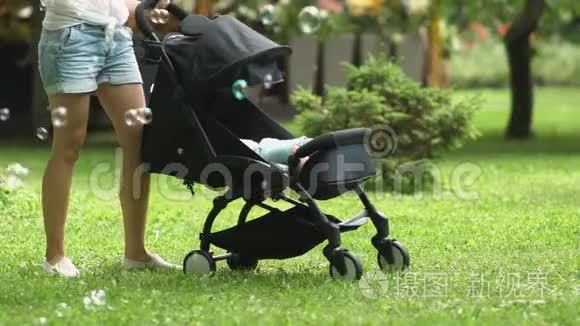 妈妈摇着婴儿车，泡泡绕着女人飞