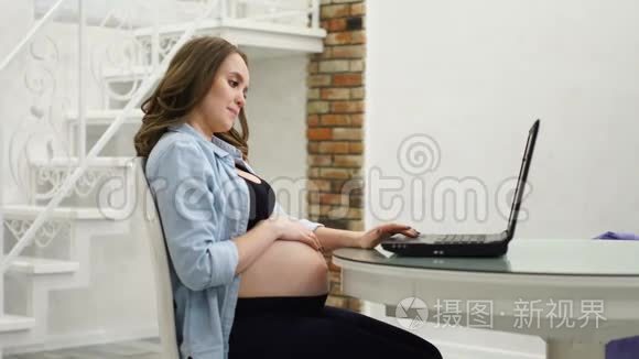 孕妇在产假期间从事业务.. 坐在电脑前抚摸着她的肚子，和她说话