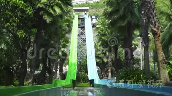 人们在暑假在水上乐园玩水上滑梯。 室外水上公园，带管和滑梯，绿色