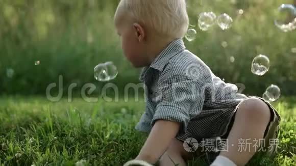小男孩坐在草地上，户外玩肥皂泡，慢动作，全高清