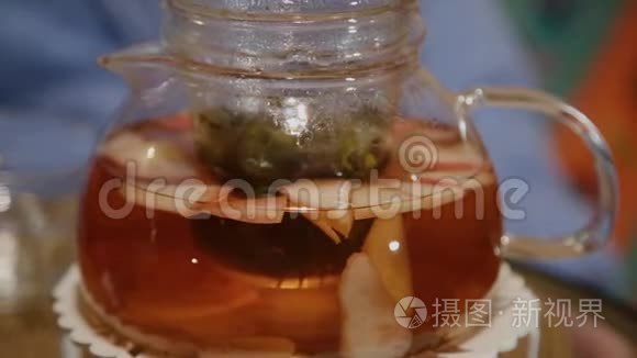 桌上摆着一个装有热茶的玻璃茶壶..