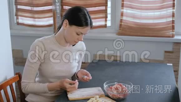 女人用肉馅包饺子，看着镜头微笑。