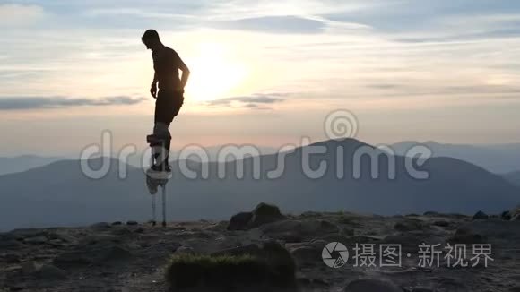 夕阳下，踩着高跷的人走在山顶上。