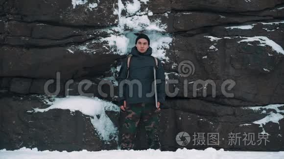 年轻人在白雪覆盖的岩壁前大笑