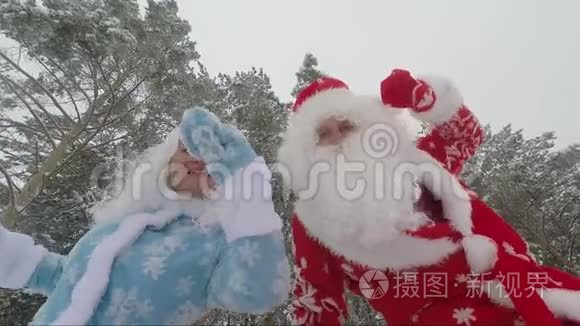 圣诞老人和他的孙女雪少女在新年的冬天森林里快乐地跳舞。