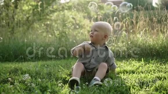 小男孩坐在草地上，户外玩肥皂泡，慢动作，全高清