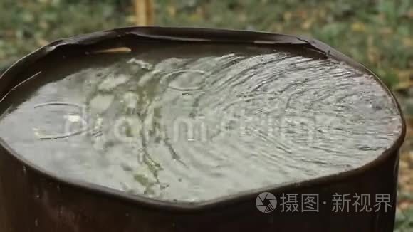 雨水流入一个生锈的旧桶。 雨滴特写。