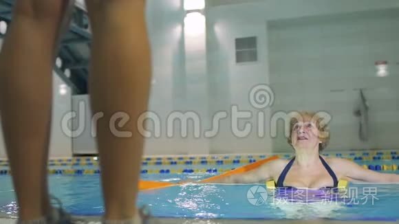 高级妇女和教练一起在游泳池里做运动