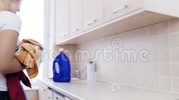 4k视频美丽微笑的女人把脏衣服放进洗衣机滚筒里，然后把它刷上