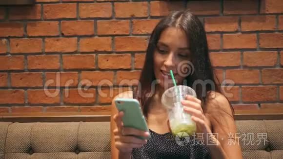 年轻迷人的女孩在咖啡厅喝抹茶，在手机上发短信。 4K. 泰国。