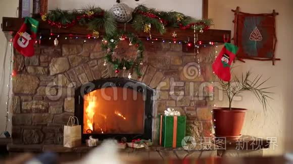 在圣诞前夜，壁炉里燃烧着花环、花环、长袜和礼品盒。 新年