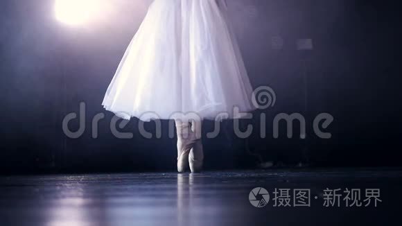 白色舞蹈芭蕾舞腿后面的黑暗舞台。