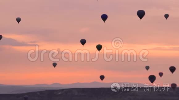 许多热气球飞过土耳其戈尔梅的山谷。 粉红色的黎明，在难以置信的地方