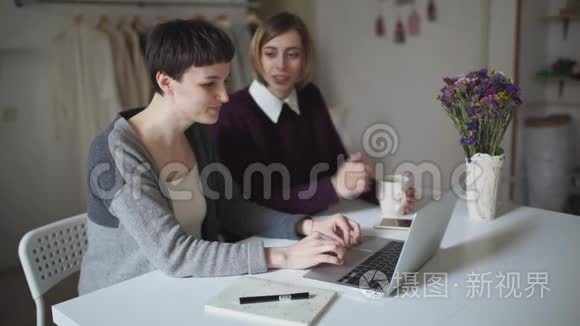 两名女学生坐在桌子上，用笔记本进行在线教育