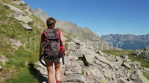 妇女在田园诗般的山景中徒步旅行。 阿尔卑斯山的夏日冒险。 慢运动，后视和相机POV..