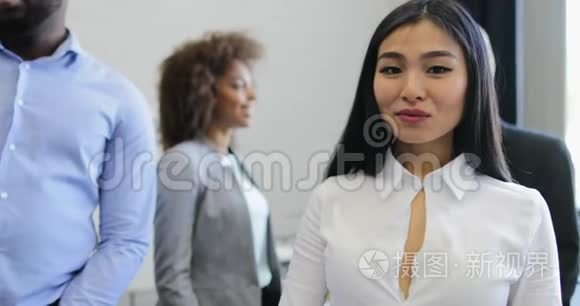 美丽的亚洲女商人走在现代创意办公室，与同事会面，交谈商务人士小组