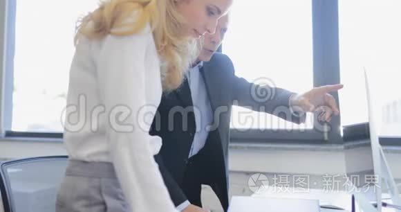 商务男女在创意办公室和电脑一起工作，两个专业的商务人士一起展示