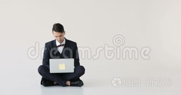 穿西装的时髦商人紧张地在白色背景的笔记本电脑上打字