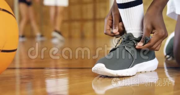 在篮球场系鞋带的高中生视频