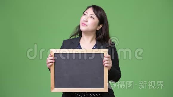 成熟美丽的亚洲女商人在黑板边思考