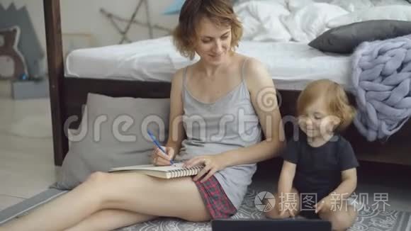 幸福家庭，可爱可爱的女儿坐在家里床边用铅笔画相册