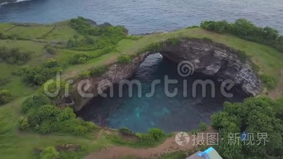 空中惊人的天然岩石拱门在美丽的破碎海滩在努沙佩尼达岛，印度尼西亚。 4K，大众游客