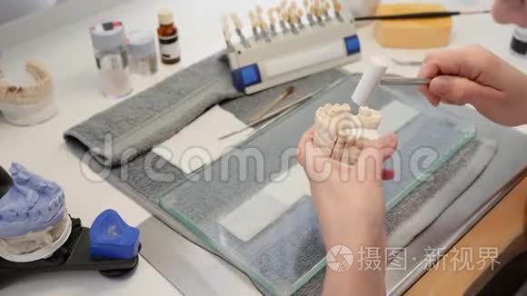 专业牙科技师将假牙插入颌骨模型，并用专用锤子敲击