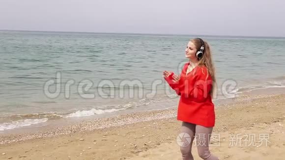 在海边的海滩上，女人用大耳机听音乐