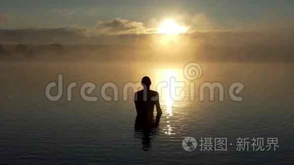 夕阳西下，一个年轻人在湖里展示了一个爱的标志