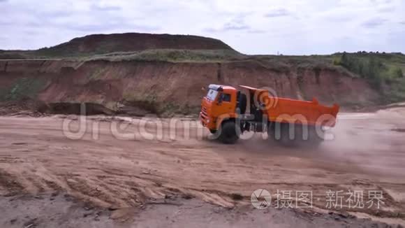 在沙土上驾驶自卸汽车的景观。 场景。 橙色自卸卡车在低地的采石场和地面