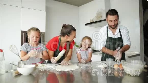 快乐的家庭烹饪在一起。 年轻的女儿正在帮助他们的父母。 他们有很多乐趣。