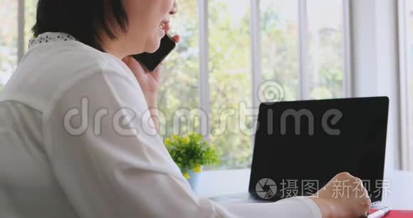 亚洲女商人用手机和笔记本电脑。