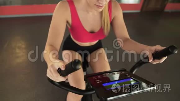 运动女性骑着固定自行车，看电子面板，运动