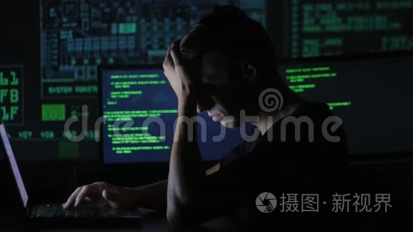 疲惫的年轻程序员在数据中心的一台电脑上工作的画像，里面装满了显示屏