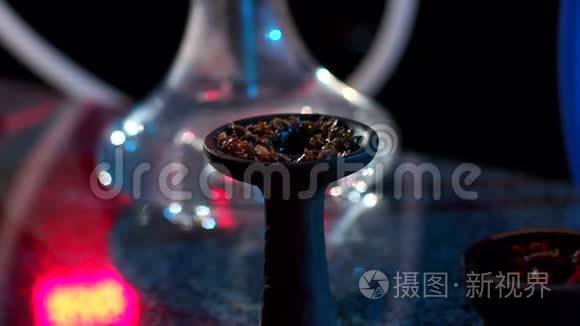 一碗水烟，在黑暗中用钳子和烟草特写。