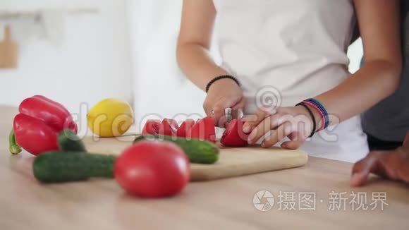 女人的特写镜头`她的手切番茄，而他的男朋友的手在桌子上。 快乐的多民族夫妻