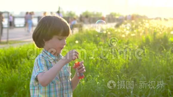 特写快乐小可爱男孩的肖像，在公园里玩肥皂泡。 小孩子在外面玩